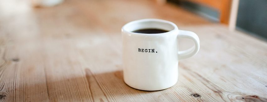 Das Bild zeigt eine weiße Kaffeetasse mit der Aufschrift BEGIN.