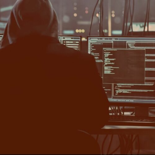 Cyber Security specialist in front of a PC with multiple monitors, displaying code-lines